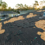 Ruined rooftop in need of repair. Wind damaged house roof with missing asphalt shingles after hurricane Ian in Florida.