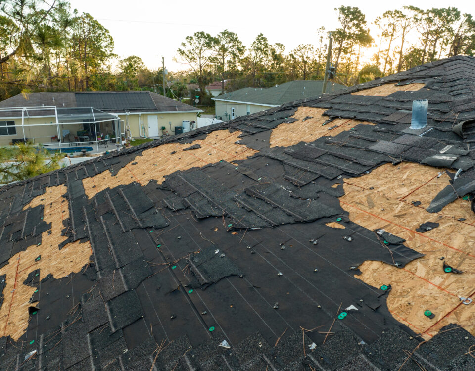 Ruined rooftop in need of repair. Wind damaged house roof with missing asphalt shingles after hurricane Ian in Florida.